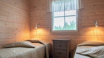 Een kamer met twee bedden, een klein houten nachtkastje en een raam met gordijn.