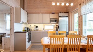 A wooden cabin interior with a kitchen, dining area, and a large window. - Katajakallio by Interhome (Konnevesi)