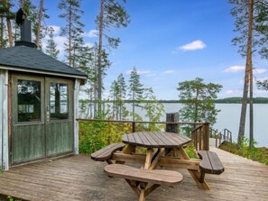 Enjoy a serene lakeside retreat with a picnic table and benches on a spacious deck overlooking the calm waters.
