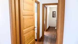 Un pasillo de madera con una puerta a la izquierda y un cuadro en la pared.