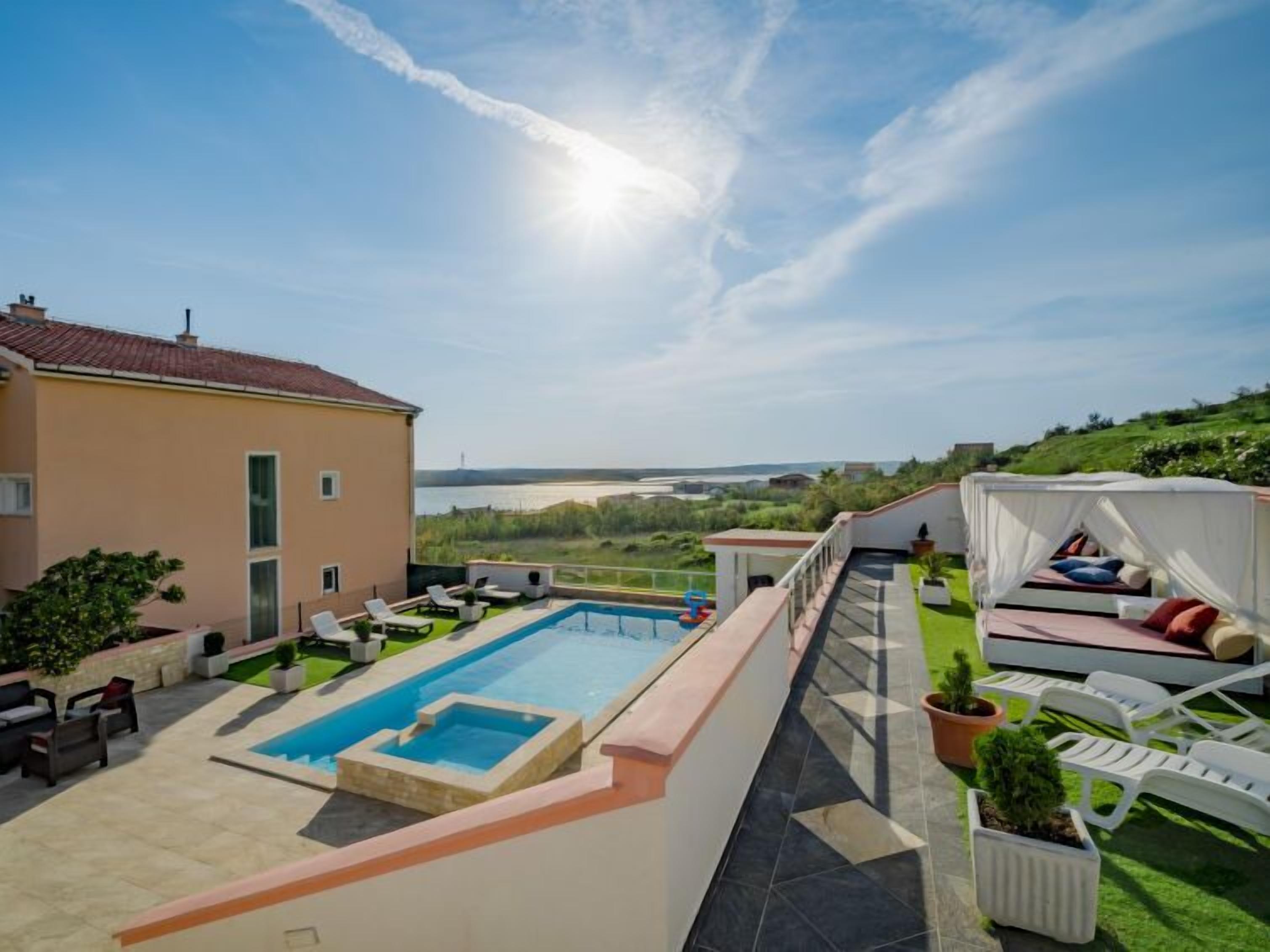 A modern villa with a swimming pool, outdoor seating, and a view of the sea.