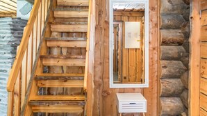 Un escalier en bois avec une rampe, un miroir et une petite boîte blanche accrochée au mur.