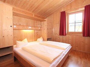 Une pièce de style cabane en bois, avec un lit, une étagère et une fenêtre avec des rideaux.
