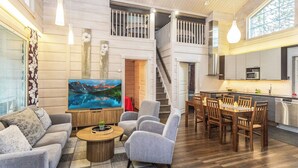 Un vaste salon doté d’un grand téléviseur à écran plat, de canapés gris, d’une table basse et d’un escalier menant à un niveau supérieur.