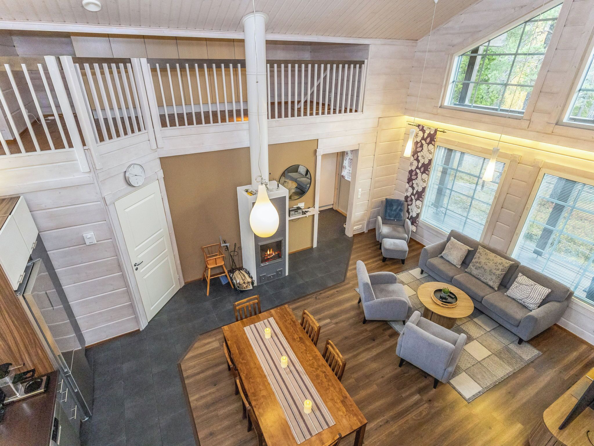 A spacious living area with a high ceiling, a fireplace, a dining table, and a cozy seating arrangement.