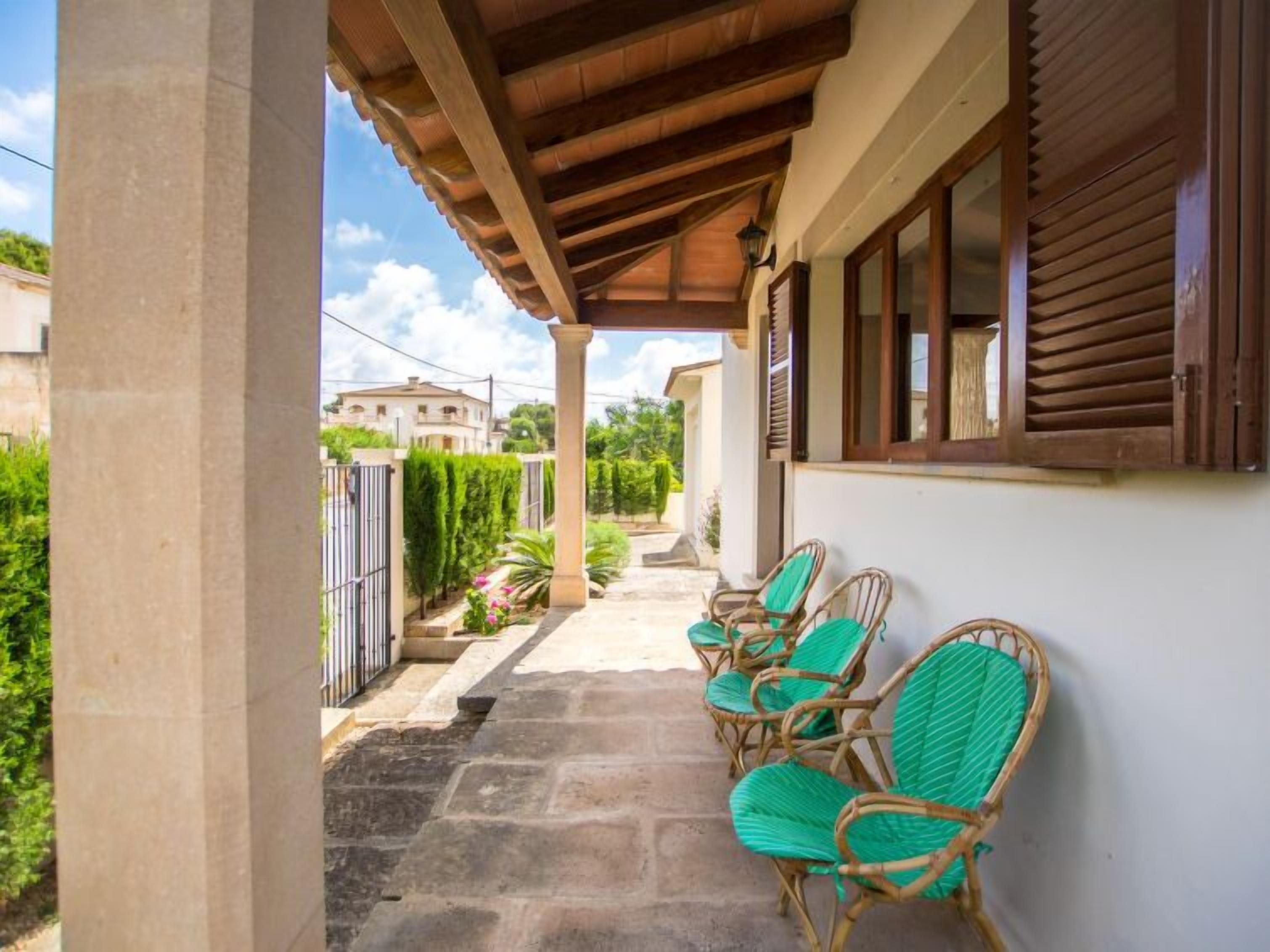 Un espace extérieur abrité, aménagé avec des chaises en osier et un sol pavé de pierres.