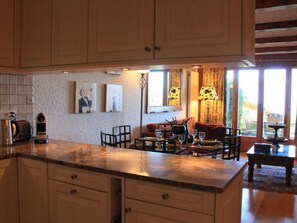 Una cocina con encimera de mármol, armarios de madera y comedor con mesa y sillas.