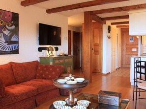 Una sala de estar con un sofá, una mesa de centro con cuencos decorativos, un televisor y un mueble de madera.