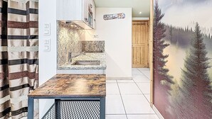 A kitchen with a granite countertop, a sink, and a wooden door. - Le Sefcotel (Val Claret) by Interhome (Tignes)