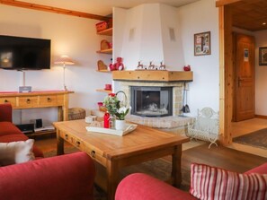 A cozy living room with a fireplace, wooden furniture, and a television.