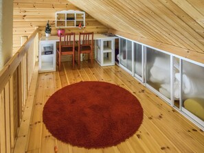 A cozy attic bedroom with a wooden floor, a red rug, a desk with a chair, and a bed with a white headboard. - Sointukallio by Interhome (Savonlinna)