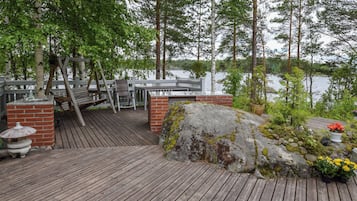 Eine Holzterrasse mit einer Backsteinmauer, einem Metallgeländer und Blick auf einen See.