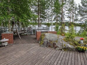 A wooden deck with a brick wall, a metal railing, and a view of a lake.