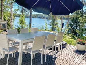 An outdoor deck with a table and chairs, overlooking a lake. - Sointukallio by Interhome (Savonlinna)