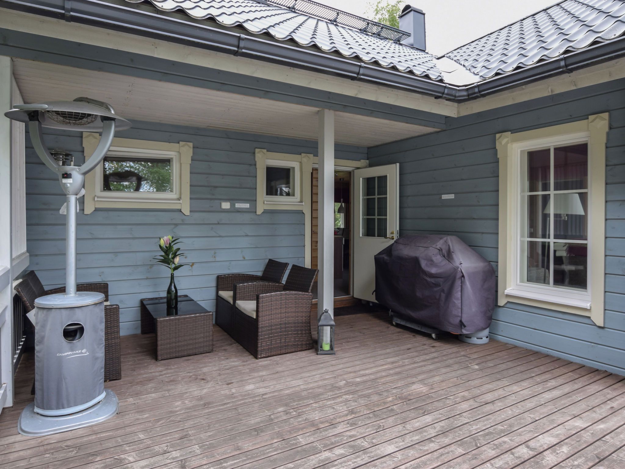 A covered outdoor seating area with a table, chairs, and a grill cover.