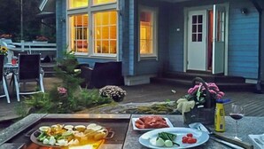 Un espacio de comedor al aire libre con una parrilla, una mesa con platos de comida y una silla.