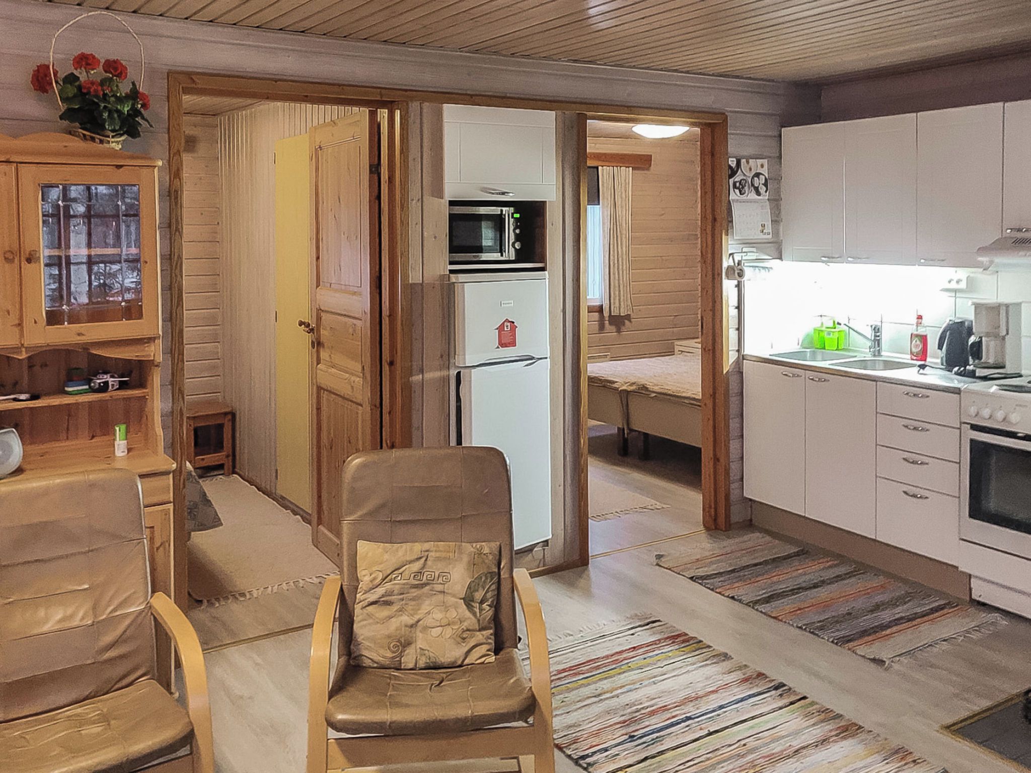 Ett kompakt bostadsutrymme med ett litet kök, en matplats och en sittgrupp med en stol.