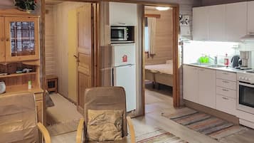 Ett kompakt bostadsutrymme med ett litet kök, en matplats och en sittgrupp med en stol.