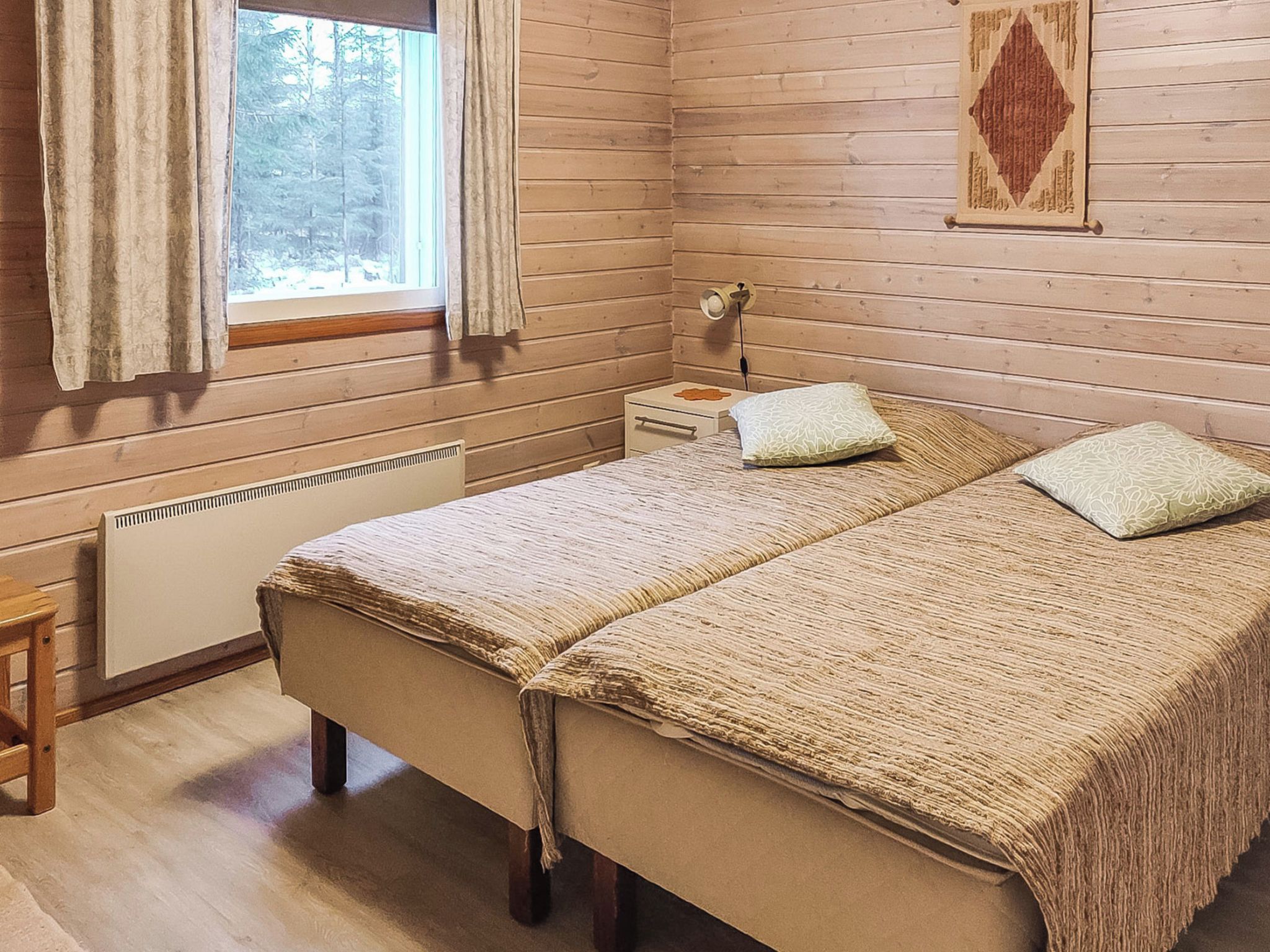 A wooden room with a bed, a nightstand, a lamp, and a radiator.