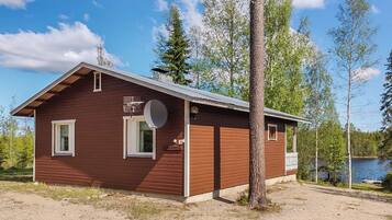 A small wooden cabin with a sloped roof, a satellite dish, and a sign that reads 'Kastirinne.'