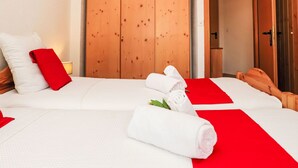 A hotel room with a large bed, wooden wardrobe, and a red accent pillow. - Mont-Fort 51 by Interhome (Siviez-Nendaz)