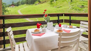 A table set outdoors with a mountain view, a chair, and a small building in the background. - Mont-Fort 51 by Interhome (Siviez-Nendaz)