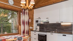 Una cocina moderna con armarios blancos, horno Bosch, lavavajillas Siemens y techo de madera.