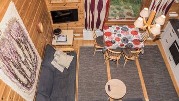 L’intérieur d’un chalet accueillant, avec un canapé, une petite table, un coin repas et un téléviseur.