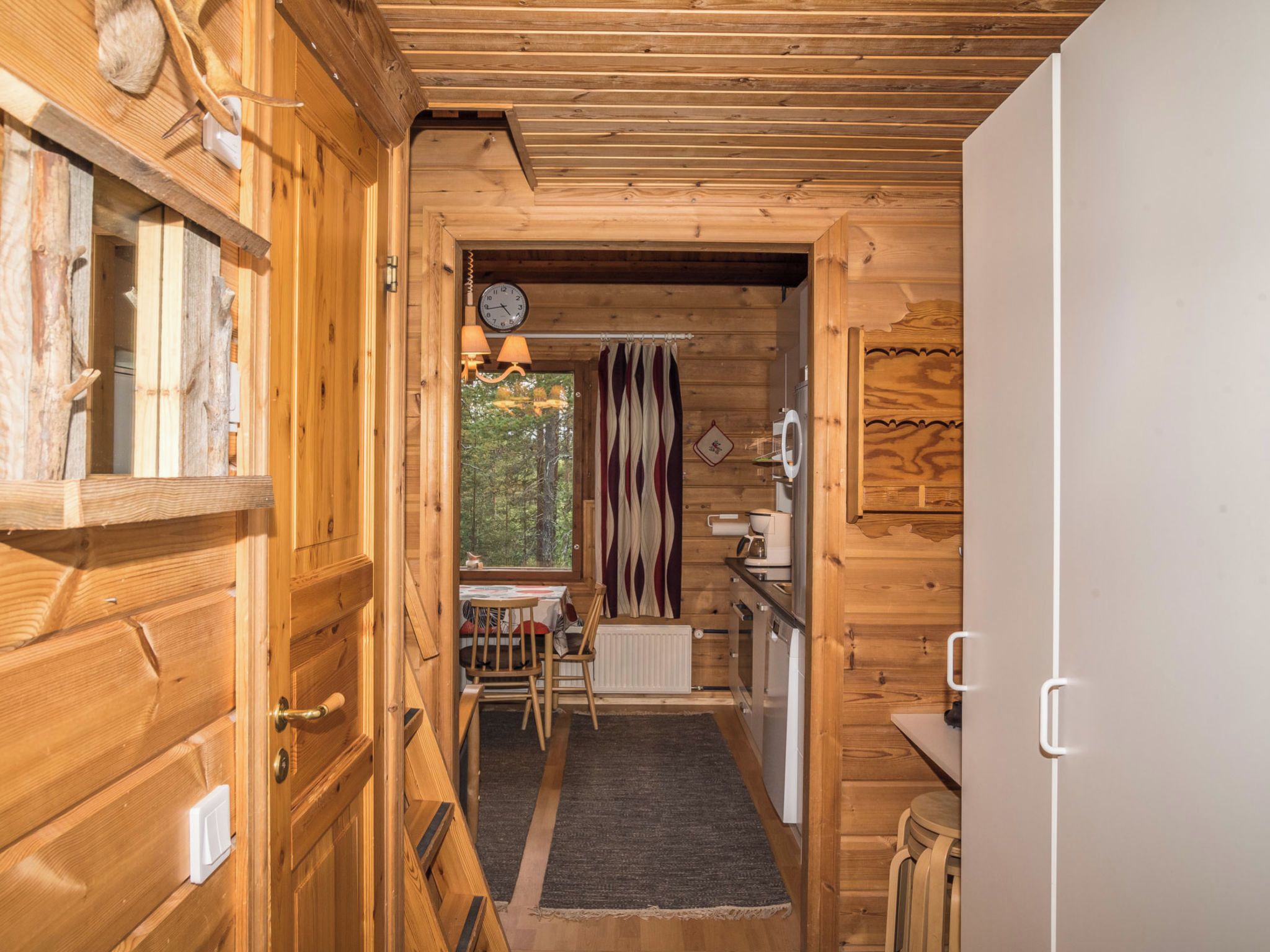 A wooden interior with a dining area, a kitchen, and a view of the outdoors.