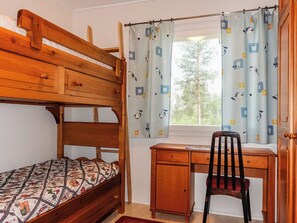 A bedroom with a bunk bed, a desk, and a chair.