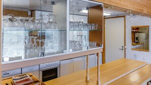 A kitchen with a wooden ceiling, a glass display cabinet with glassware, and a wooden table. - Itätullinkievari by Interhome (Salla)