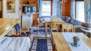 A cozy cabin interior with a dining area, a sofa, a television, and a small kitchenette. - Itätullinkievari by Interhome (Salla)
