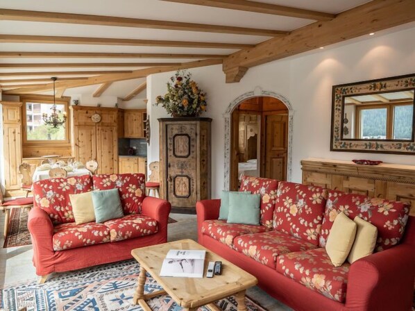 A cozy living room with two red floral sofas, a wooden coffee table, and a patterned rug. - Chesa Spuonda Verde 1.7 by Interhome (St. Moritz)