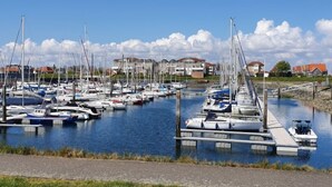 A marina with numerous boats docked, a clear sky, and residential buildings in the background. - Zeeuwse Cottage Wemeldinge by Interhome (Wemeldinge)