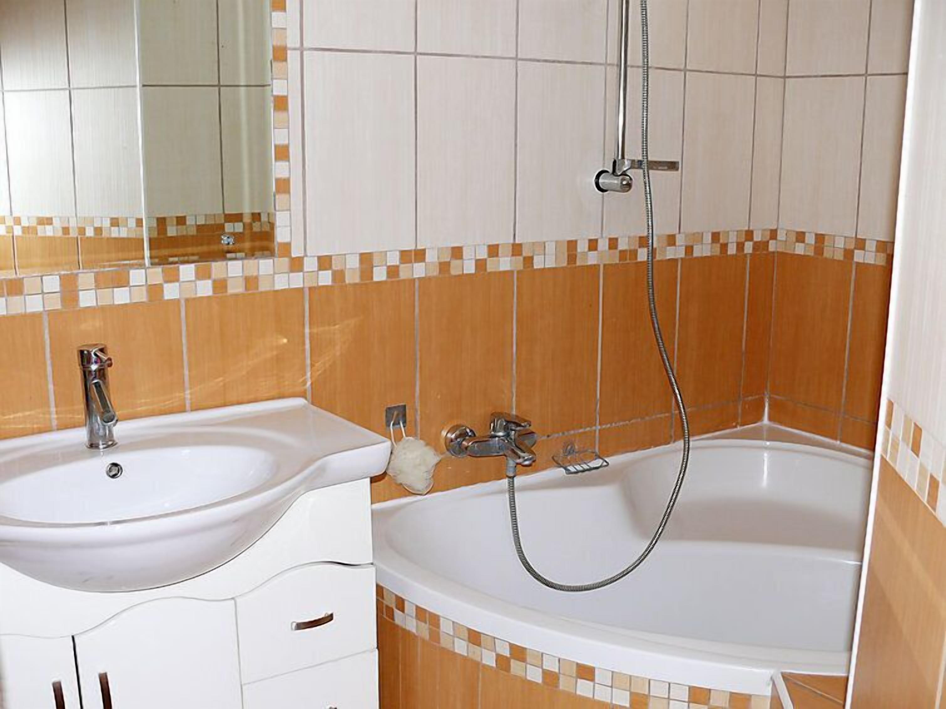 Een badkamer met een wastafel, spiegel en bad.