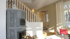 Ein modernes Wohnzimmer mit Kamin, Treppe und Blick ins Freie.