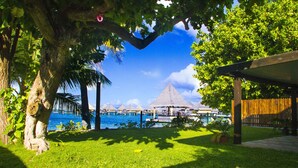 A tropical resort with a pool, thatched-roof structures, and a wooden fence.