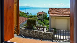 A balcony with a stone wall, a tiled roof, and a view of a lake and mountains. - Apartment Andrea by Interhome (Opatija/Bregi)