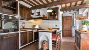 A rustic kitchen with wooden cabinets, a built-in oven, and a tiled backsplash.