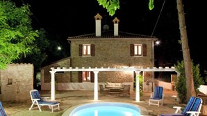 A stone house with a pool and outdoor seating.