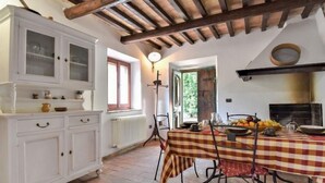 A rustic kitchen with a checkered tablecloth, wooden beams, and a white cabinet.