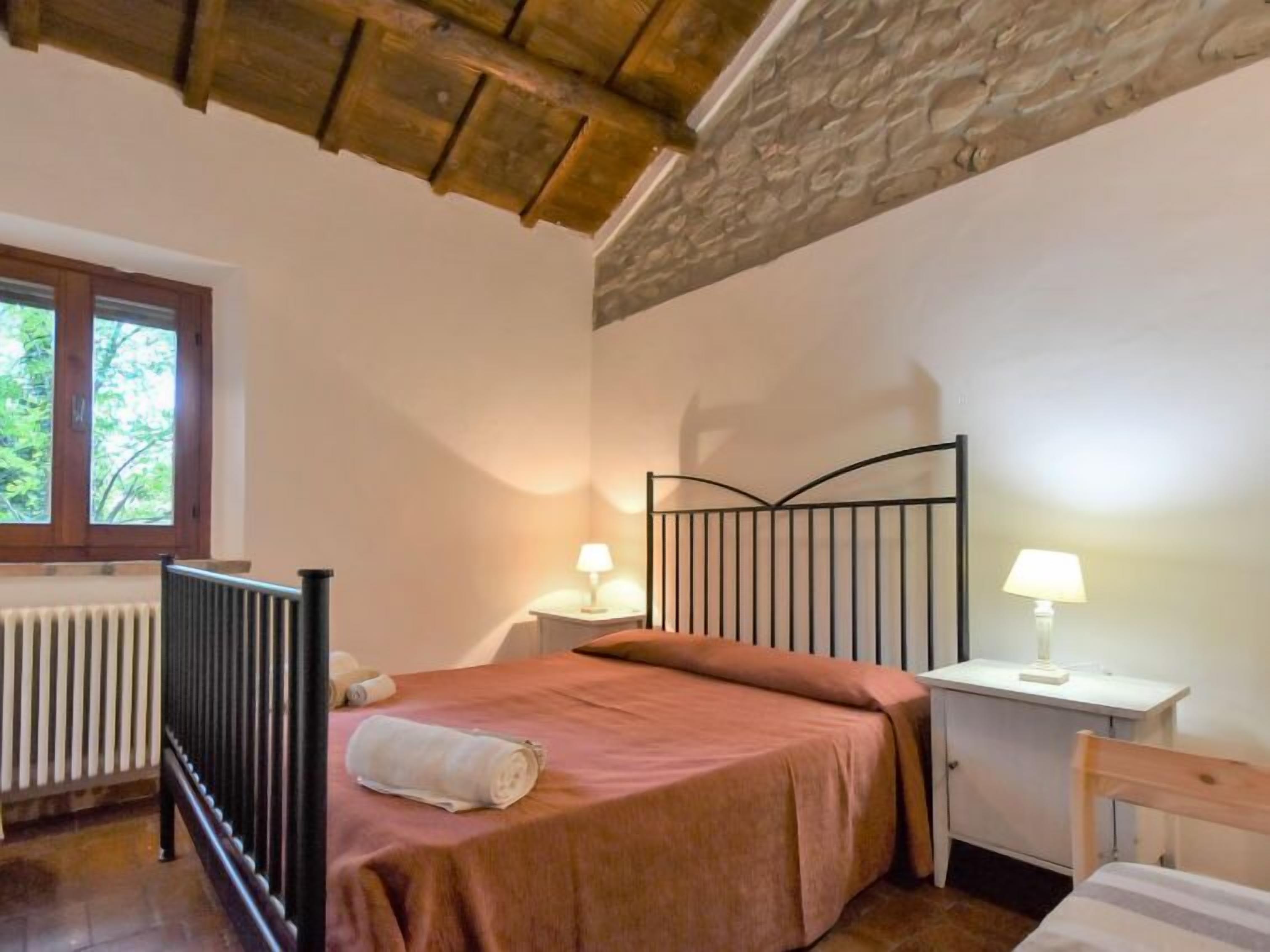 Un dormitorio con cama, mesita de noche, escritorio y radiador.