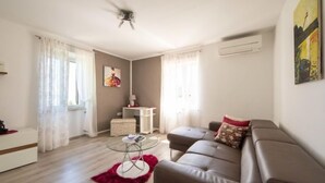 Un salon moderne avec un canapé, une table basse en verre et un petit bureau blanc.