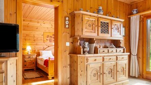 A wooden cabin interior with a bed, a TV, a cabinet with decorative items, and a window with curtains. - Als man zählte 1989 by Interhome (St Niklaus)