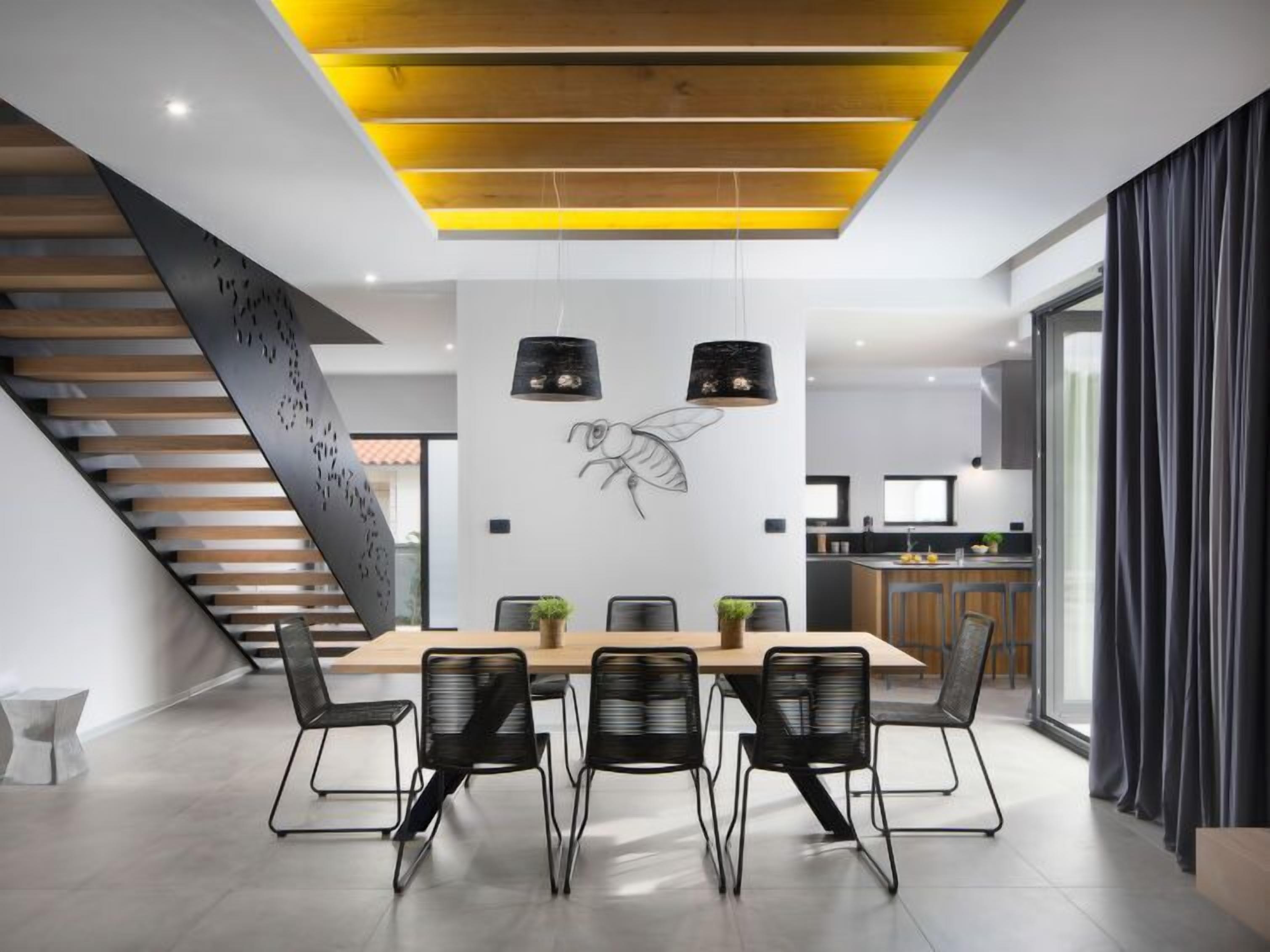 A modern dining area with a wooden table, black chairs, and a unique ceiling design.
