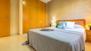 Ein Hotelzimmer mit einem großen Bett, einem Holzschrank und einem Nachttisch mit Lampe.
