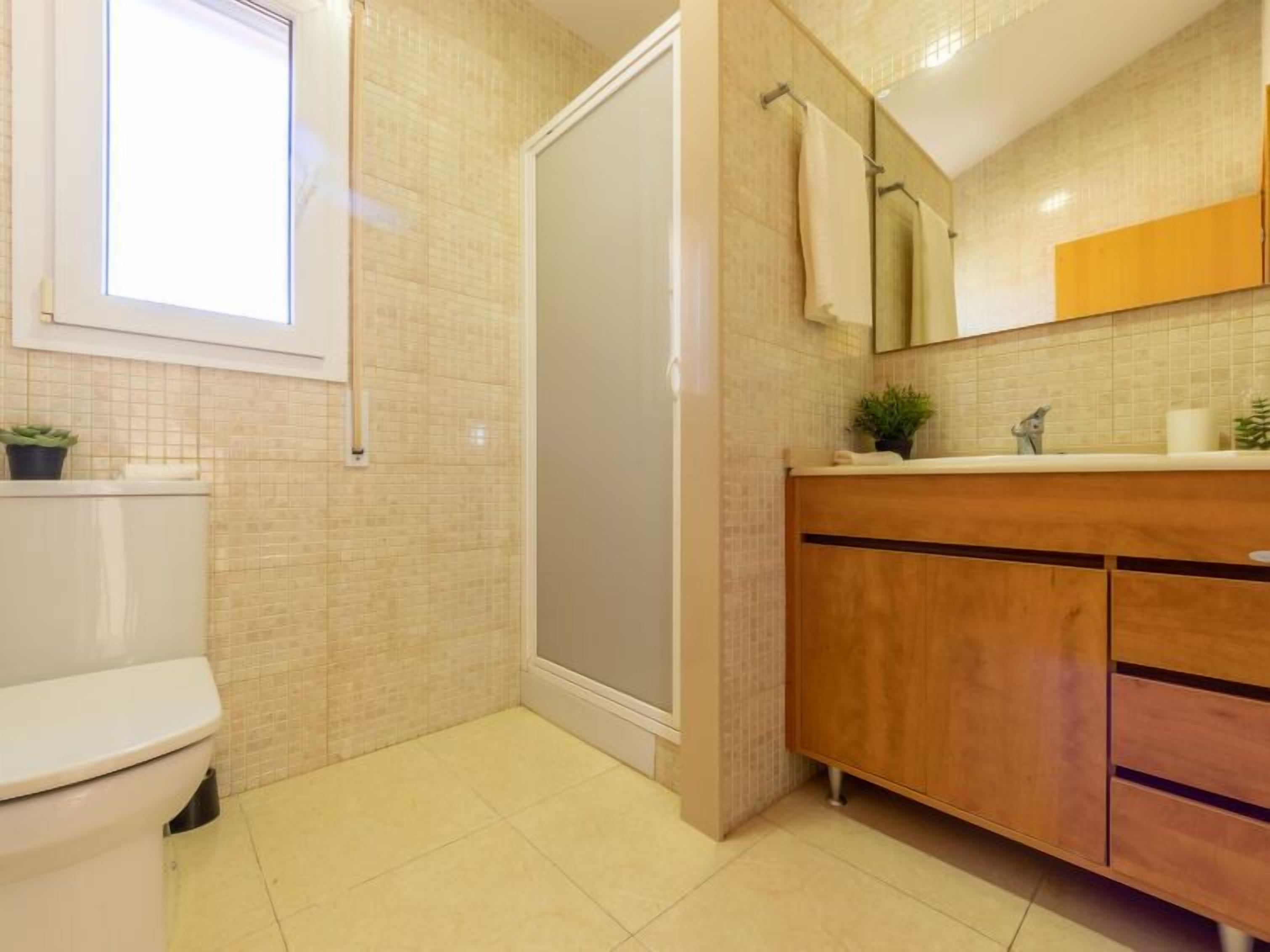 A modern bathroom with a toilet, a shower, and a vanity with a mirror.