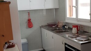 A compact kitchen with white cabinets, a stainless steel stove, and a window providing natural light.