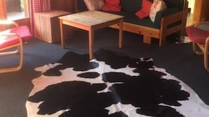 A cozy room with a wooden interior, a sofa with cushions, a small table, and a cowhide rug.