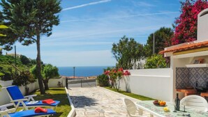 Un patio con suelo de piedra, una mesa con sillas y vistas al mar.